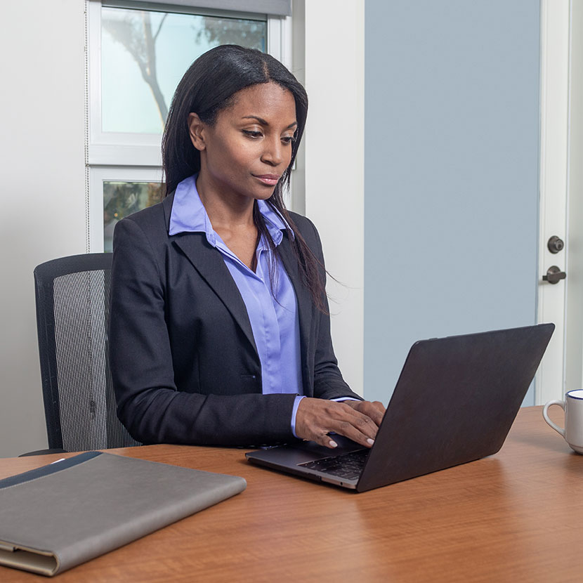 A woman on a laptop reads that TruStage Payment Guard has been recognized as a Benzinga Global Fintech Awards Runner-Up.