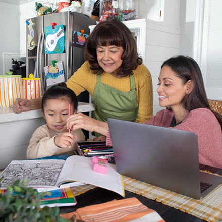 A grandmother, daughter and grandchild coloring pictures at the table