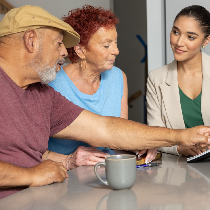 A man and woman sit with a financial advisor and discuss different ways to build wealth.