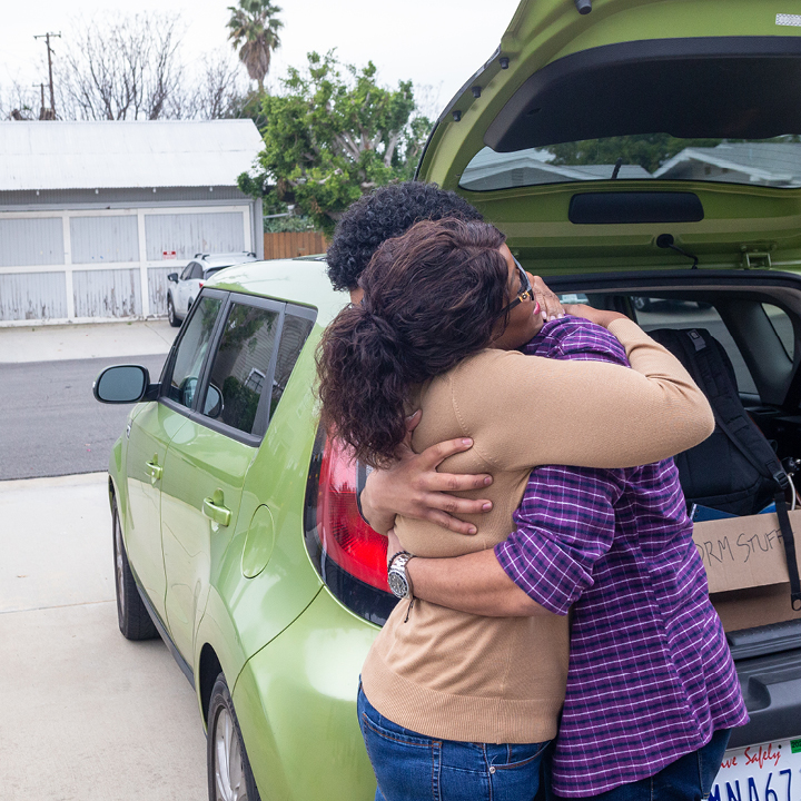 A mother and son hugging by his vehicle