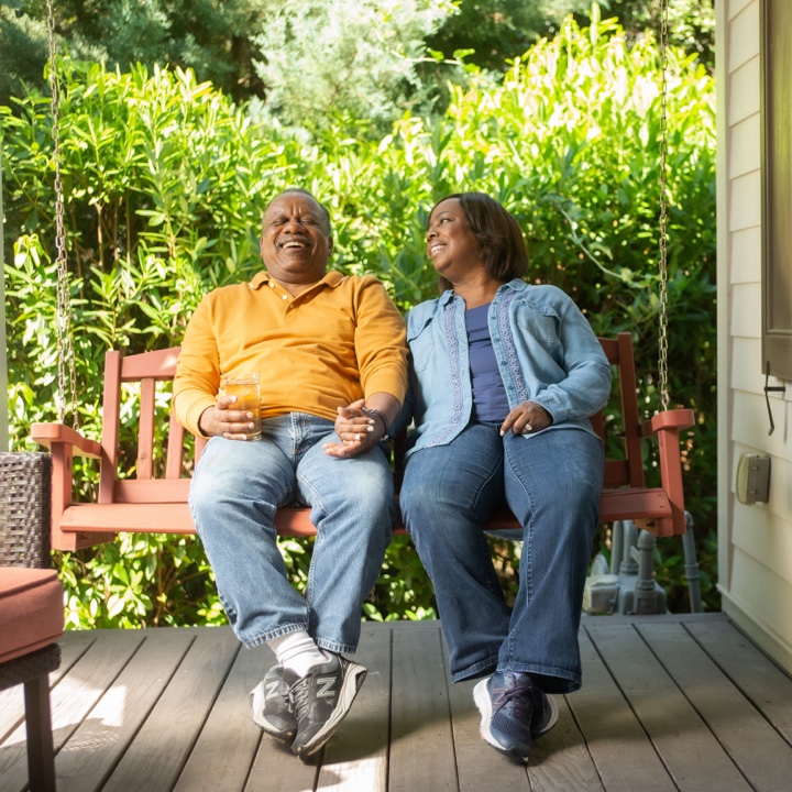 A couple relaxes on their porch swing confident in what they know about homeowners insurance