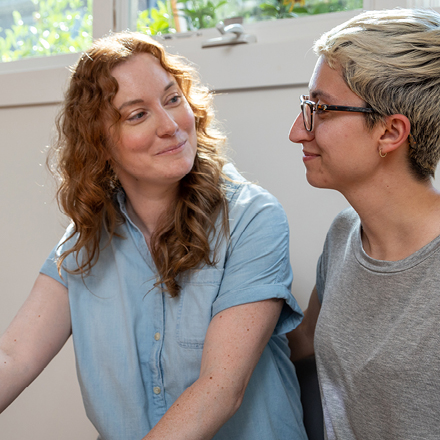 Two women smiling at each other in their apartment