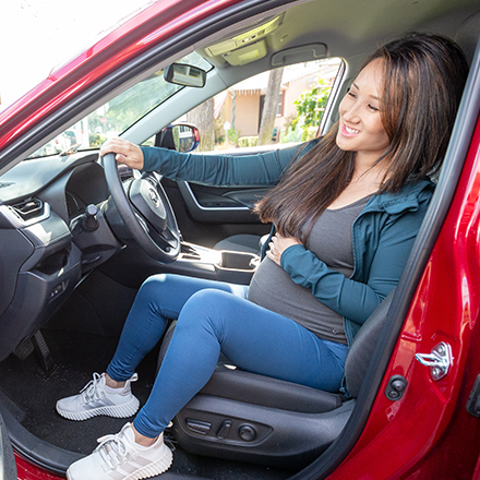 A pregnant woman getting out of her vehicle