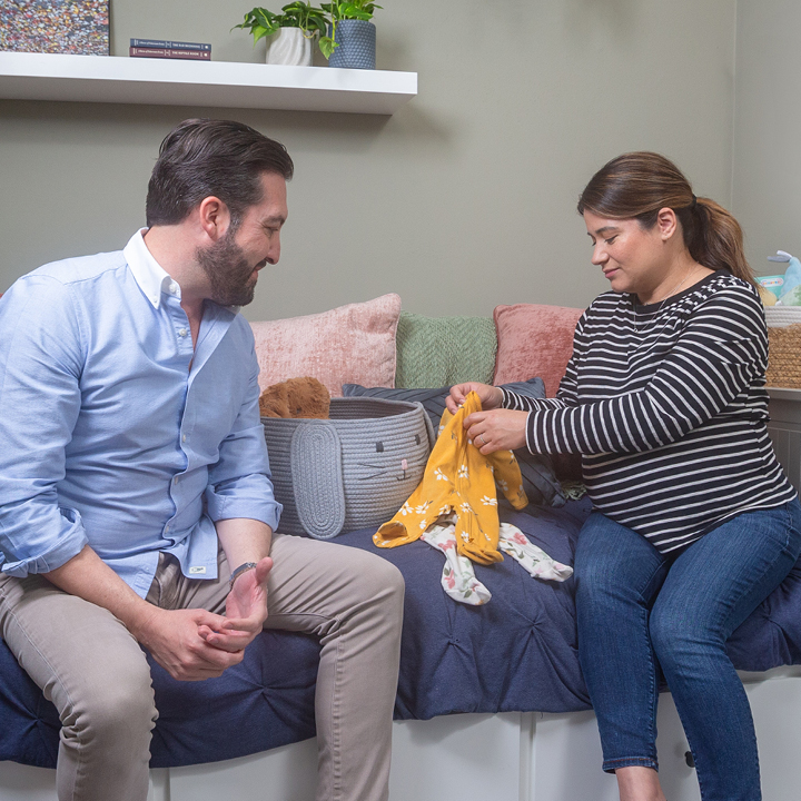 A couple folding clothes, discussing their life insurance needs once their baby is born