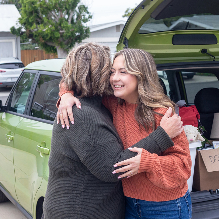 Mother and daughter hugging outside of a car