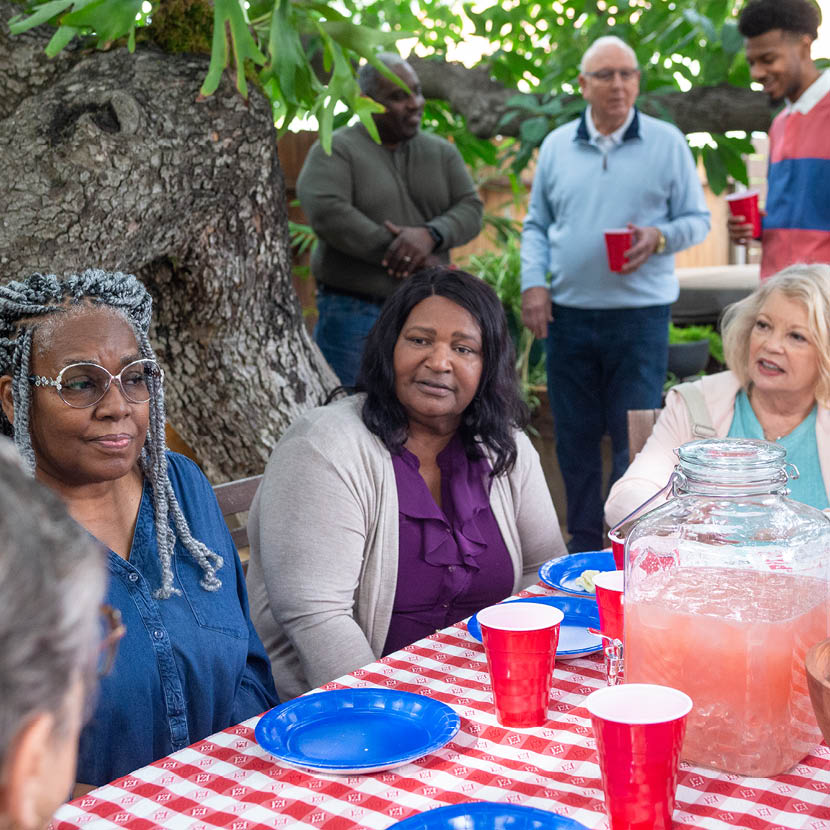 Three women sitting at picnic table discussing TruStage insurance