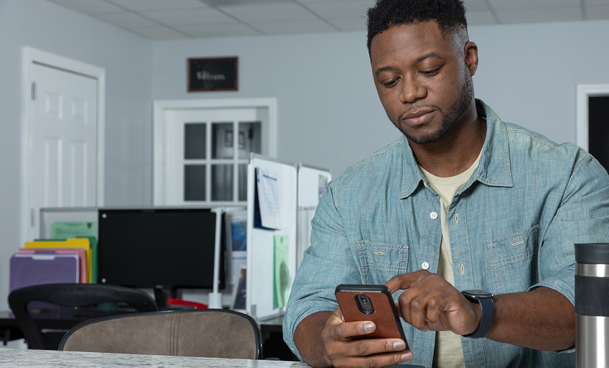 A young man checks his TruStage™ retirement portfolio's performance on his smartphone