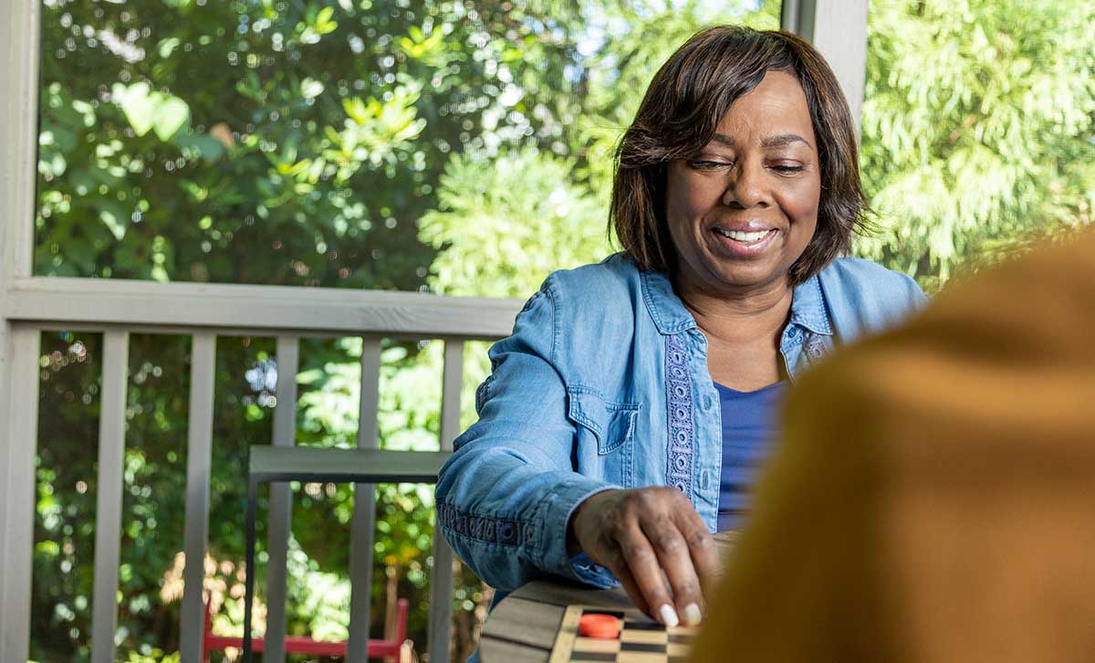 A women enjoys a game of Checkers and feels secure about her financial future, thanks to TruStage™ MaxProtect Fixed Annuity.