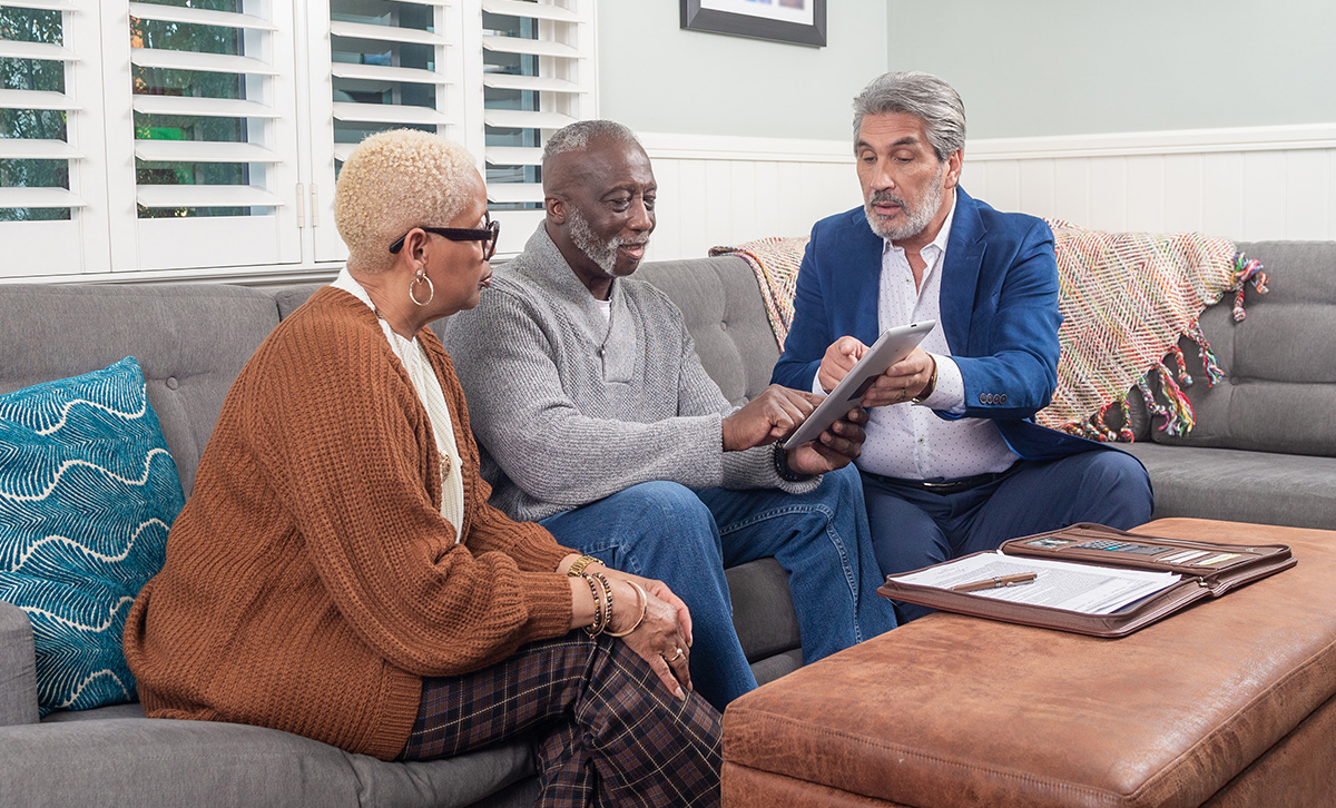 A retired African-American couple and their financial professional discuss the performance of their TruStage™ Annuity.