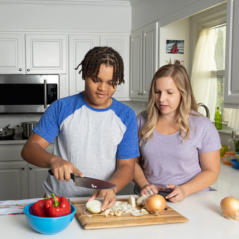 A mom and her son cut vegetables in the kitchen, as mom has piece of mind she's better protected by a TruStage™ RILA.