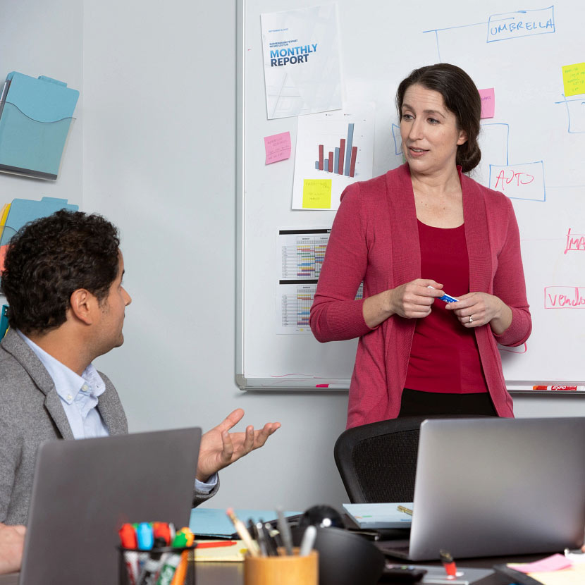 Employees meeting in front of a dry erase board