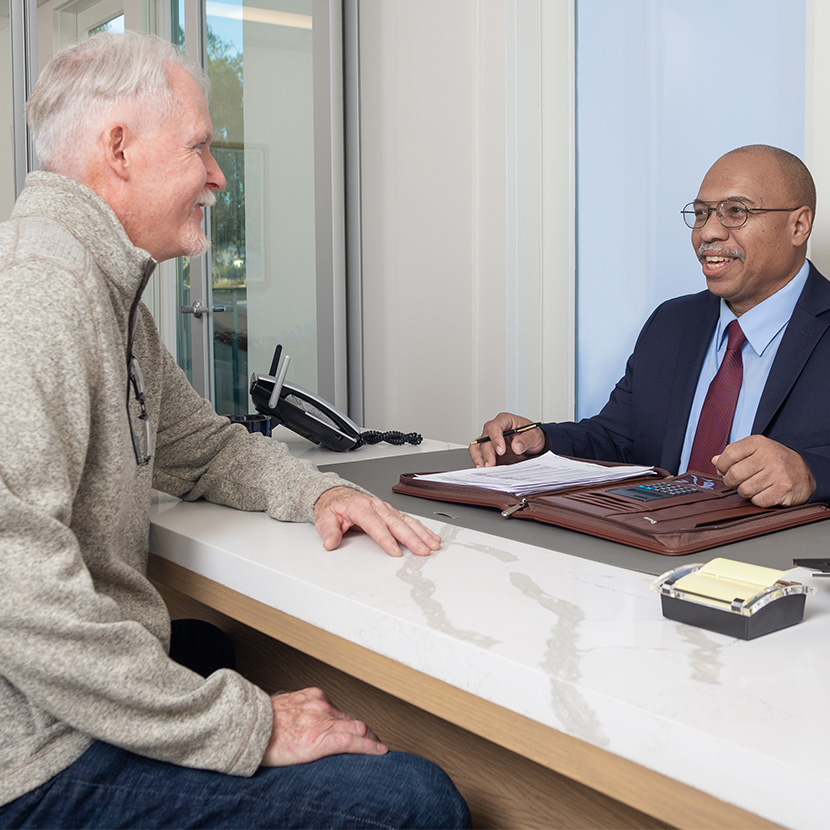 Two men in a conference room discuss TruStage™ Executive Benefits resources while seated at a table. 