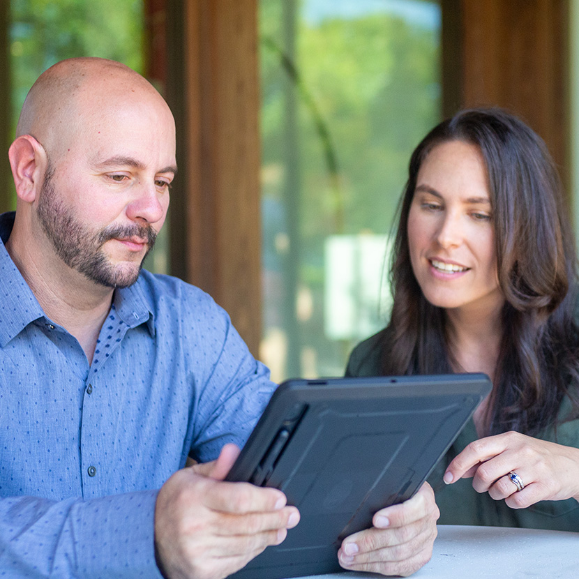 A man and a woman, both seated and with a tablet, are discussing their TruStage™ retirement portfolio. 