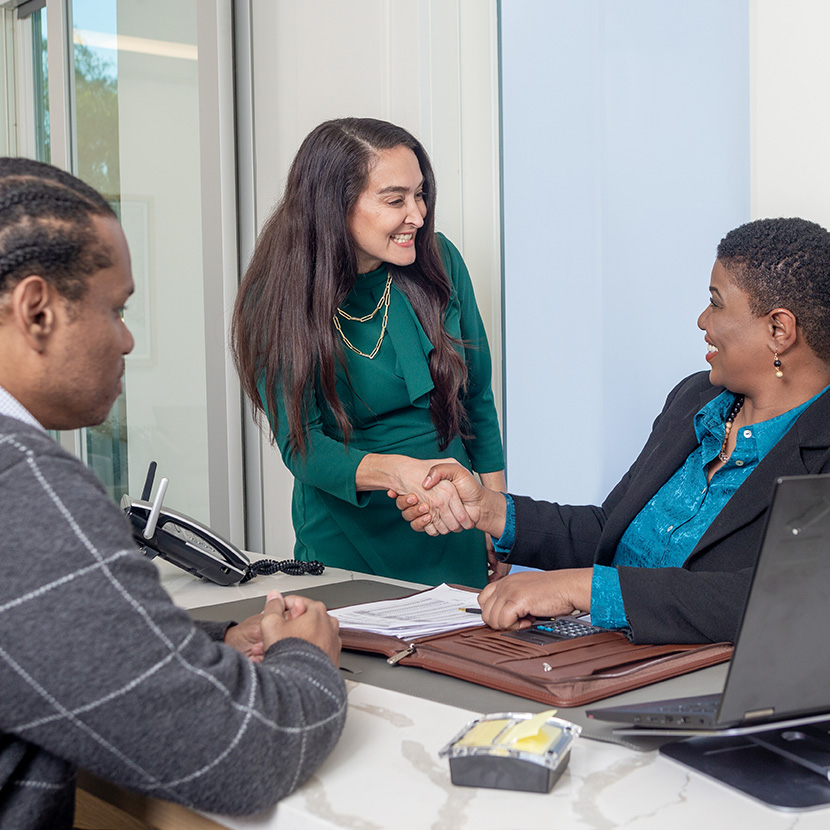 Two women shake hands in a conference rooms after discussing Executive Benefits Solutions from TruStage™