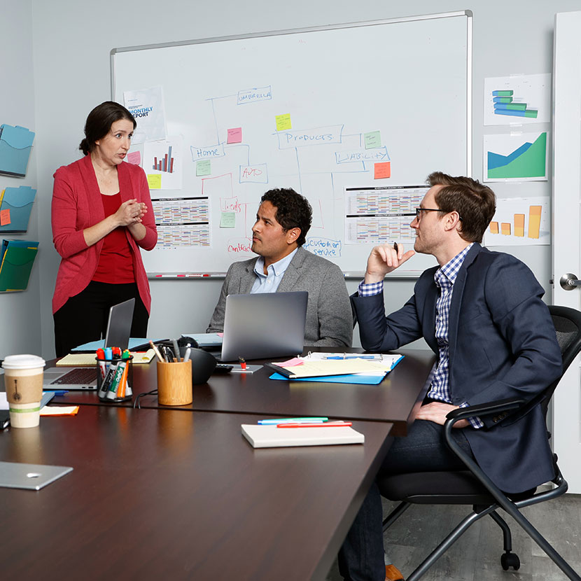 Financial professionals in a conference room discuss how best to educate their clients about retirement.