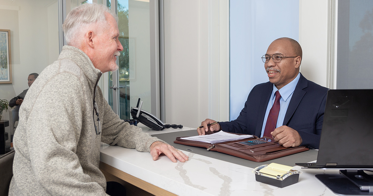 Two men in a conference room discuss TruStage™ Executive Benefits resources while seated at a table. 