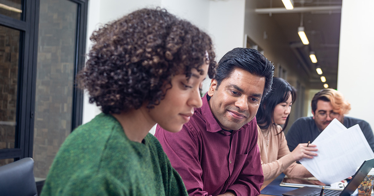 A group of employees in a conference room discuss Workplace Solutions materials provided by TruStage™